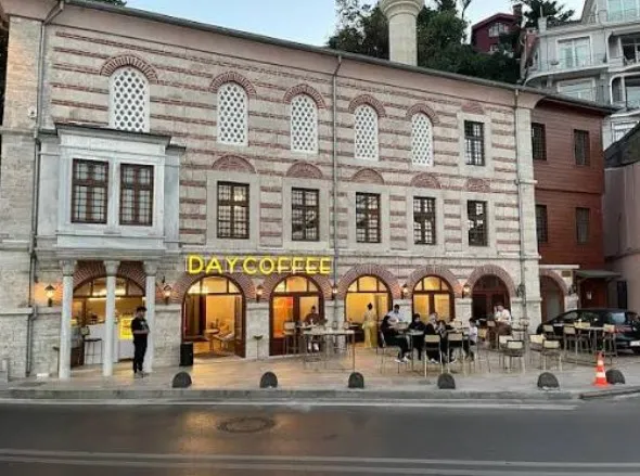 Akşam ışığında cephe, DAY COFFEE tabelası ve dış oturma alanı