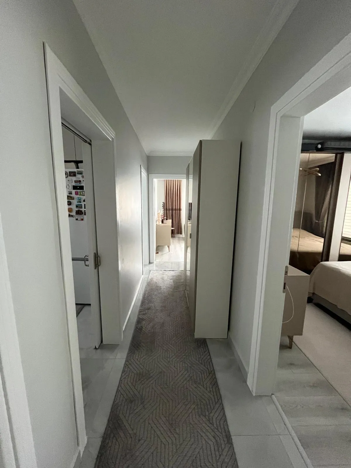 Beyaz panel kapılı hol, geometrik desenli yolluk ve odalara açılan koridor